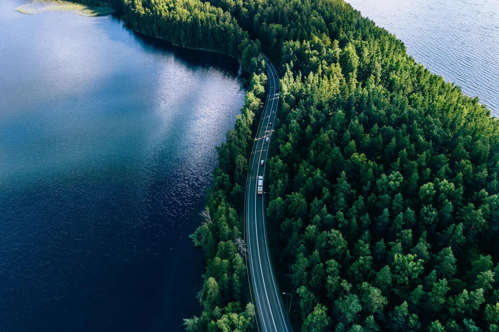 Aerial view of a road through Nordic forest between lakes